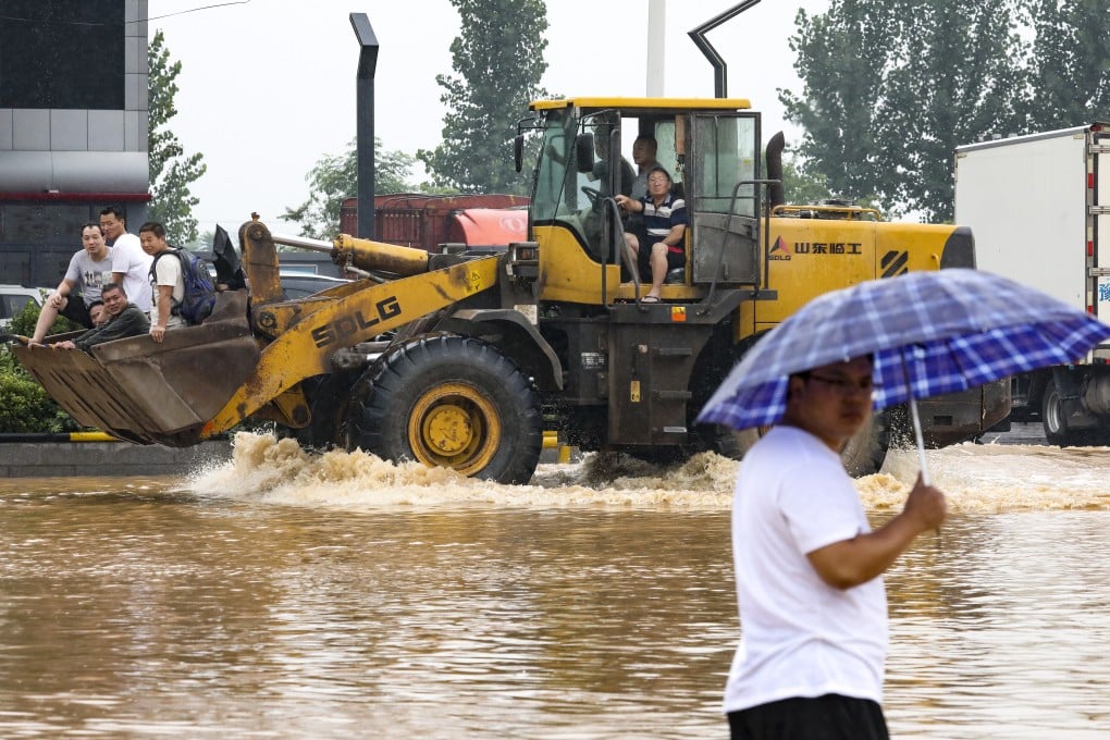 A resident wades through floodwater near the highway entrance to Xinxiang in Henan province on Thursday. Photo: Simon Song