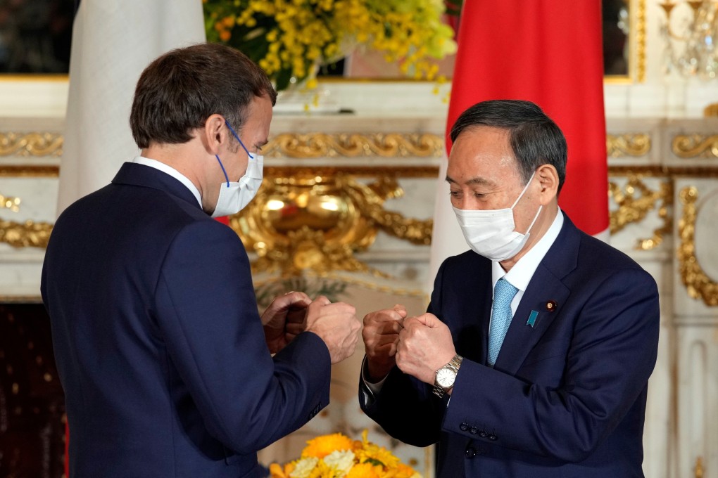 Japanese Prime Minister Yoshihide Suga (right) greets French President Emmanuel Macron in Tokyo on Saturday. Photo: Reuters