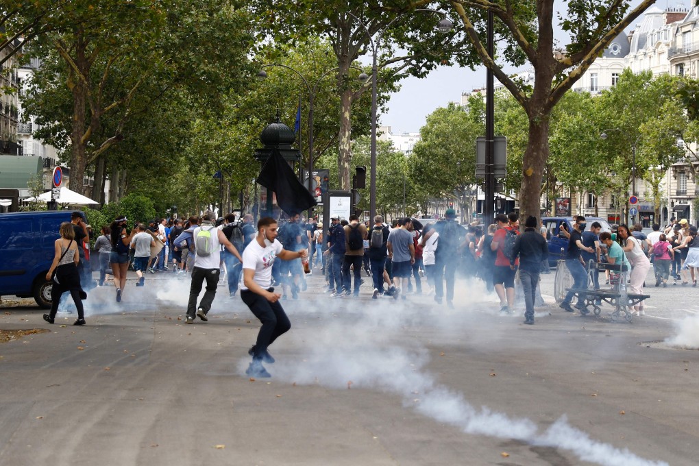 Protesters walk past tear gas smoke in Paris. Photo: AFP