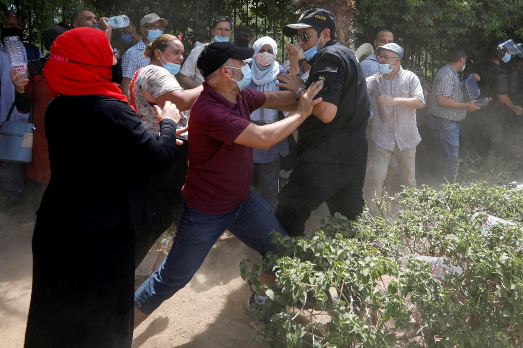 A supporter of Tunisia’s biggest political party, the moderate Islamist Ennahda, scuffles with a police officer near the parliament building in Tunis, Tunisia, on Monday. Photo: Reuters