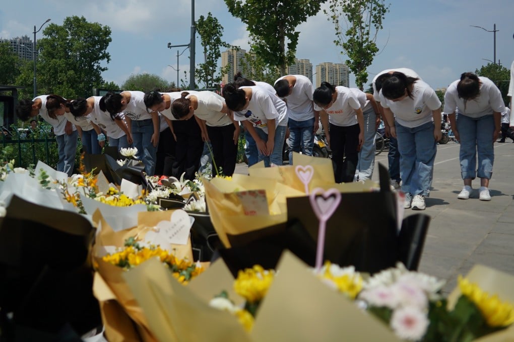 People bow to pay their respects on Tuesday outside the entrance to a subway station in Zhengzhou where more than a dozen people died after a record-breaking downpour. Photo: AP