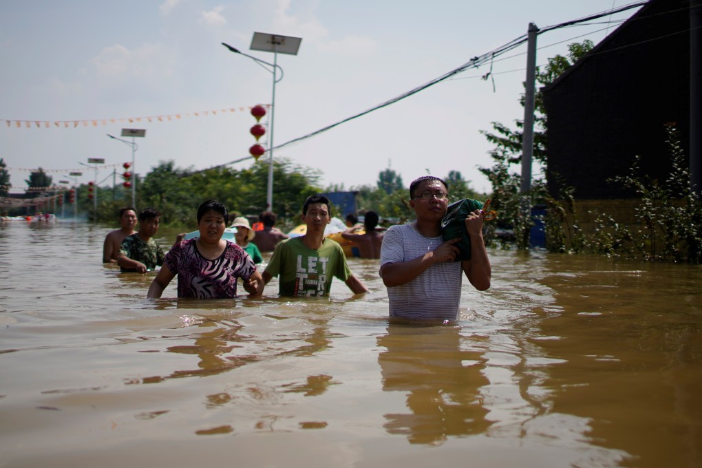 People wade through floodwater following heavy rainfall at a village in Xinxiang, Henan province on Saturday. Photo: Reuters