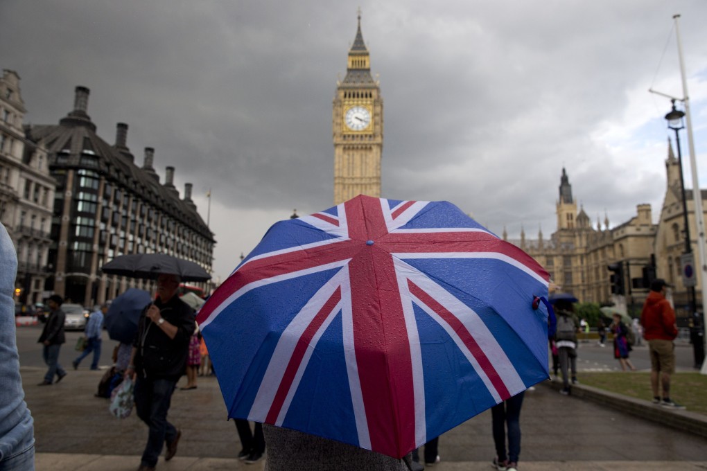 A pedestrian shelters from the rain beneath a Union flag-themed umbrella in central London. Photo: AFP