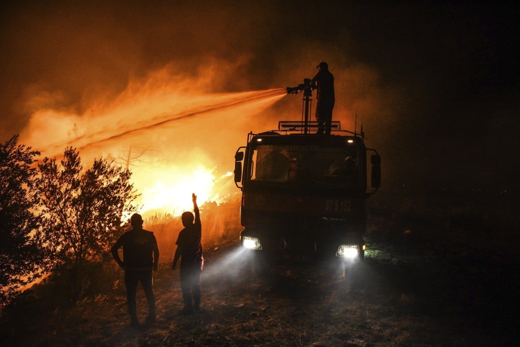 Firefighters spray water as they try to get the fire under control in Kirli village near the town of Manavgat in Antalya, Turkey on Friday. Photo: AP