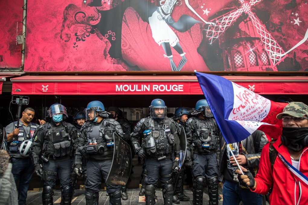 French anti-riot forces stand guard in front of the Moulin Rouge during a protest against the coronavirus health pass in Paris, France on Saturday. Photo: EPA-EFE