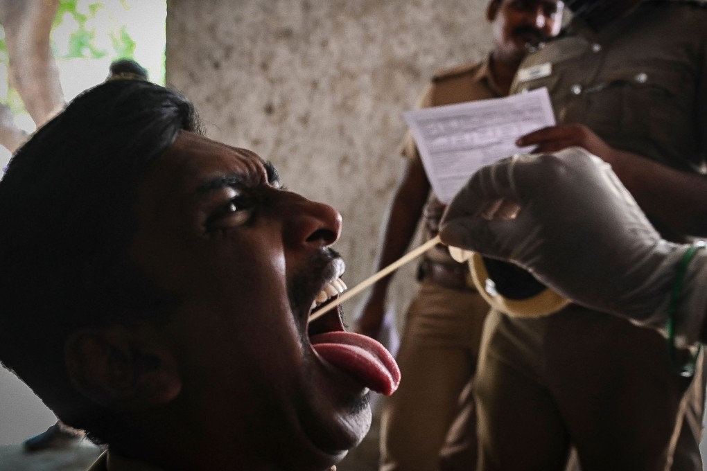 A health worker takes a swab sample from security personnel during a screening in Chennai. Photo: AFP