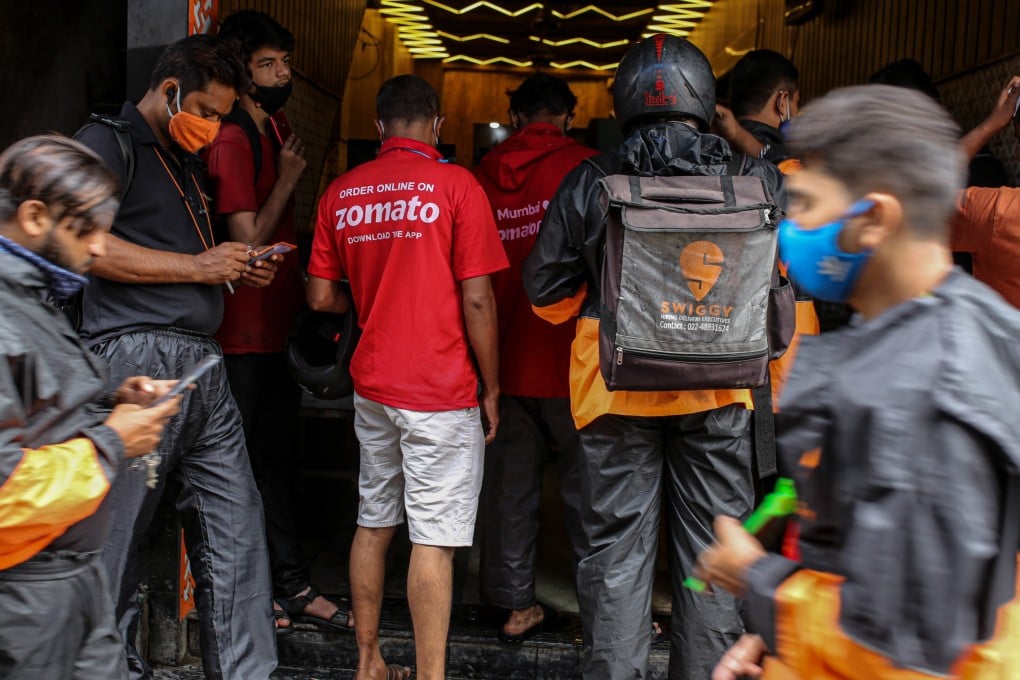 Delivery riders for Zomato and Swiggy, two Indian start-ups, wait to collect orders outside a restaurant in Mumbai. Photo: Bloomberg