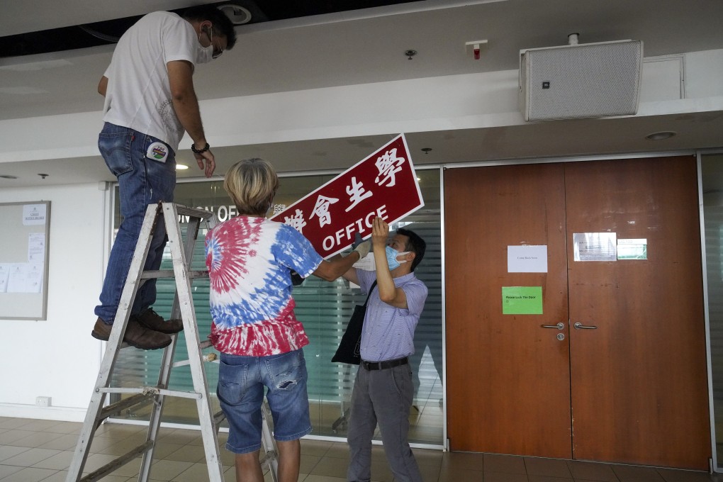 Workers remove the sign from the University of Hong Kong’s student union office after the school stripped it of recognition last month. Photo: Winson Wong