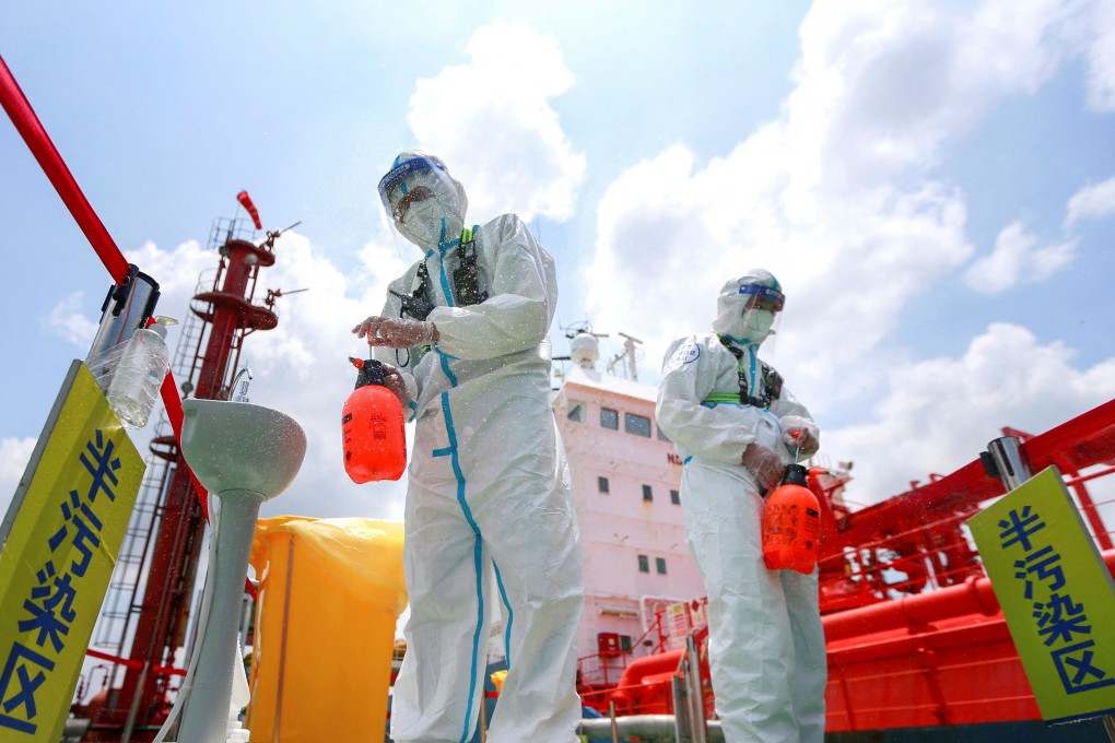 Police officers wearing protective gear spray disinfectant at Nanjing port. Photo: AFP