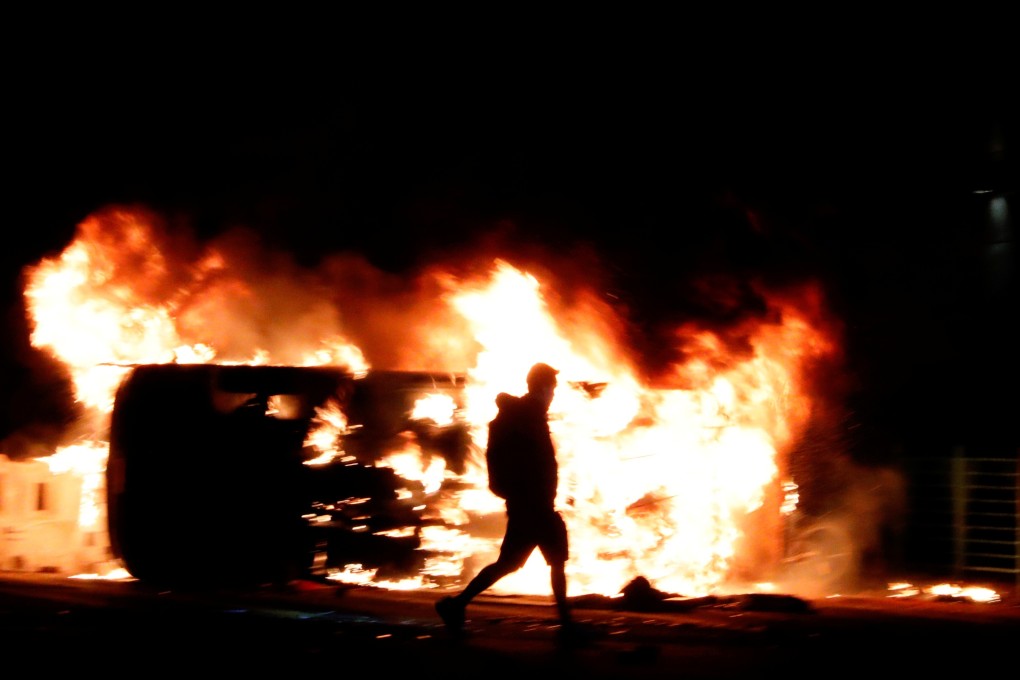 An anti-government protester walks past a burning vehicle during a protest in Tseung Kwan O, Hong Kong, in November 2019. Photo: Reuters
