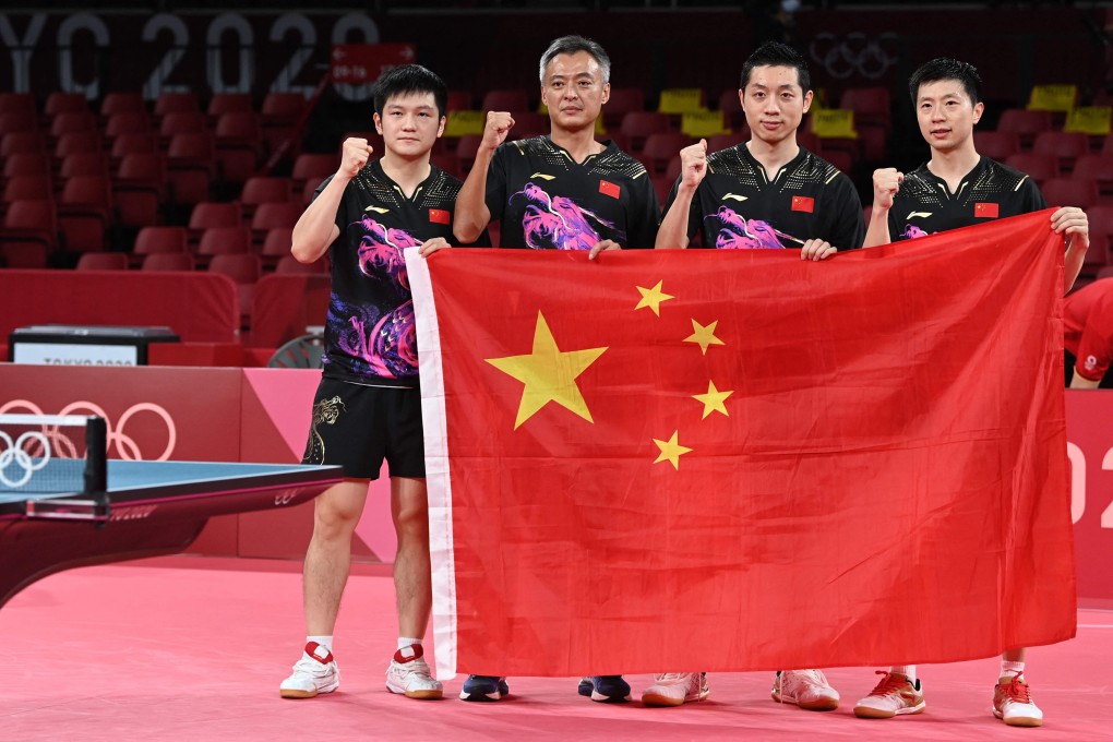 (From right) China’s Ma Long, Xu Xin, coach Qin Zhijian and Fan Zhendong pose with their national flag after winning the table tennis men’s team gold. Photo: AFP