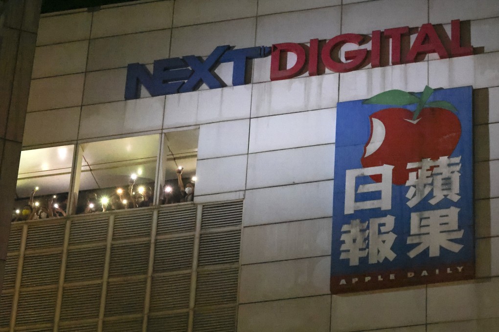 Apple Daily staff members flash their smartphone flashlight to show their gratitude of the supporters outside the complex. Photo: Dickson Lee