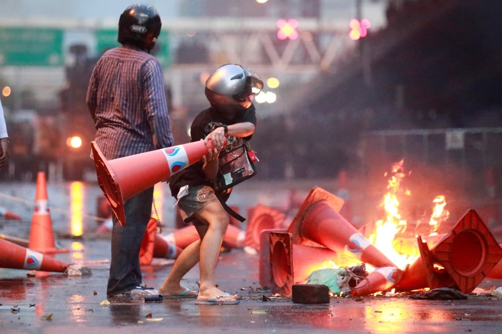 A protester attempts to fling a traffic cone in Bangkok on Tuesday. Photo: Reuters