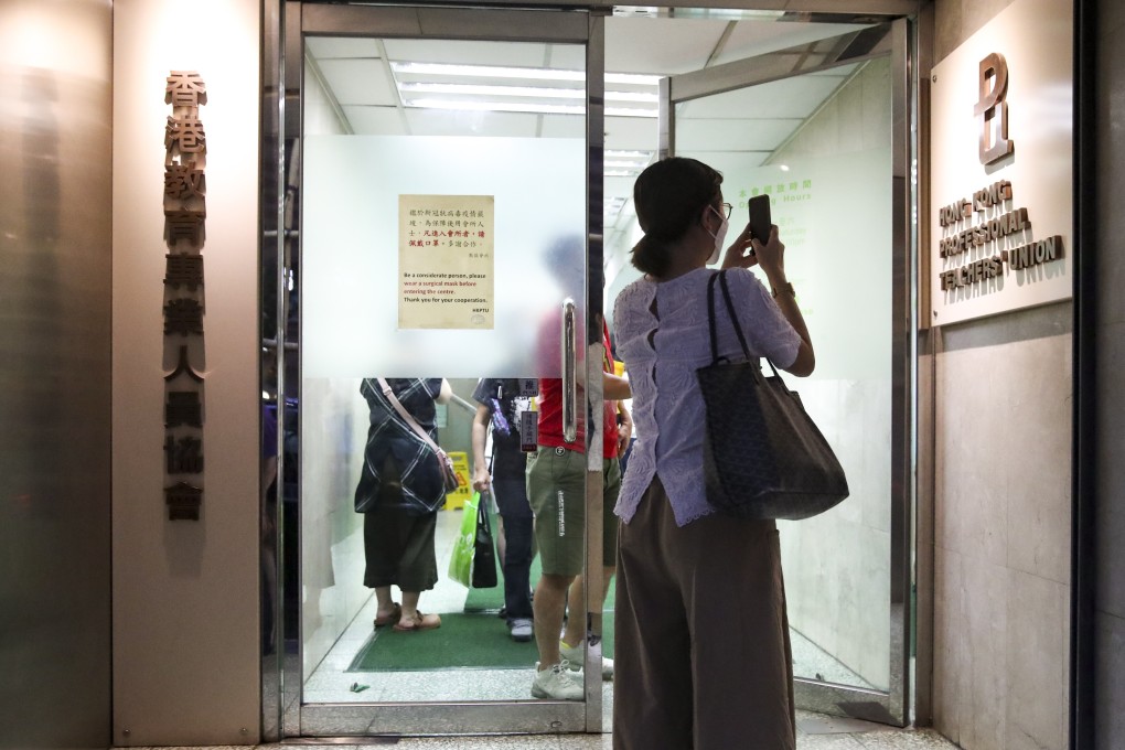 A member of the Hong Kong Professional Teachers’ Union takes a photo outside its Causeway Bay offices after the group said it would disband on Tuesday. Photo: Edmond So