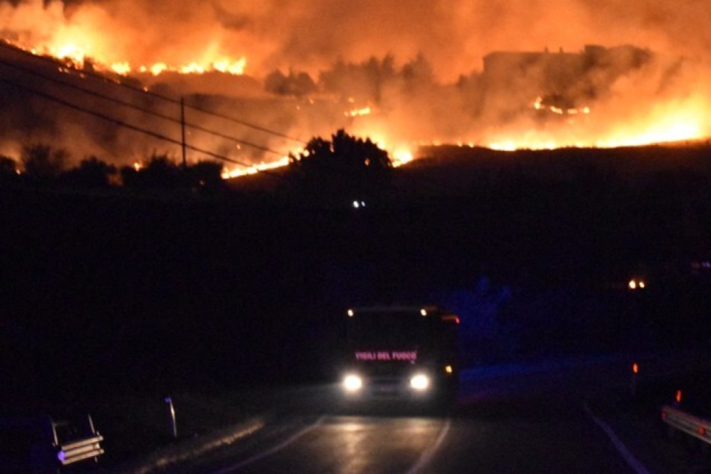 A fire engine is seen on the road as flames rage around Palermo, Sicily on Tuesday. Photo: Vigili del Fuoco via AFP