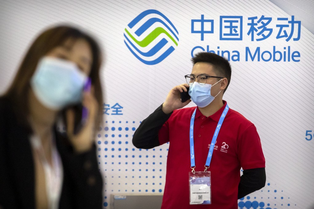 People wearing face masks talk on their cellphones near a booth for telecommunications firm China Mobile at the PT Expo in Beijing in October 2020. Photo: AP