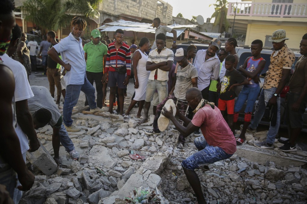 A man digs with a stone through the rubble of a house destroyed by the earthquake in Les Cayes, Haiti. Photo: AP
