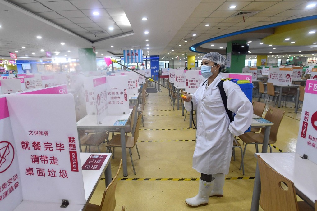 A staff member sprays disinfectant in the dining hall of a Lenovo factory in Wuhan, Hubei province on Friday. Photo: STR/AFP