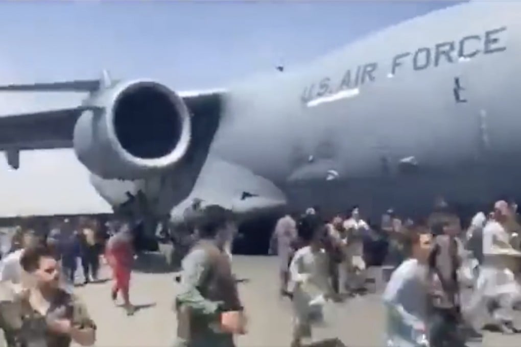 Hundreds of people run alongside a US Air Force C-17 transport plane as it moves down a runway of the international airport, in Kabul, Afghanistan. Photo: AP