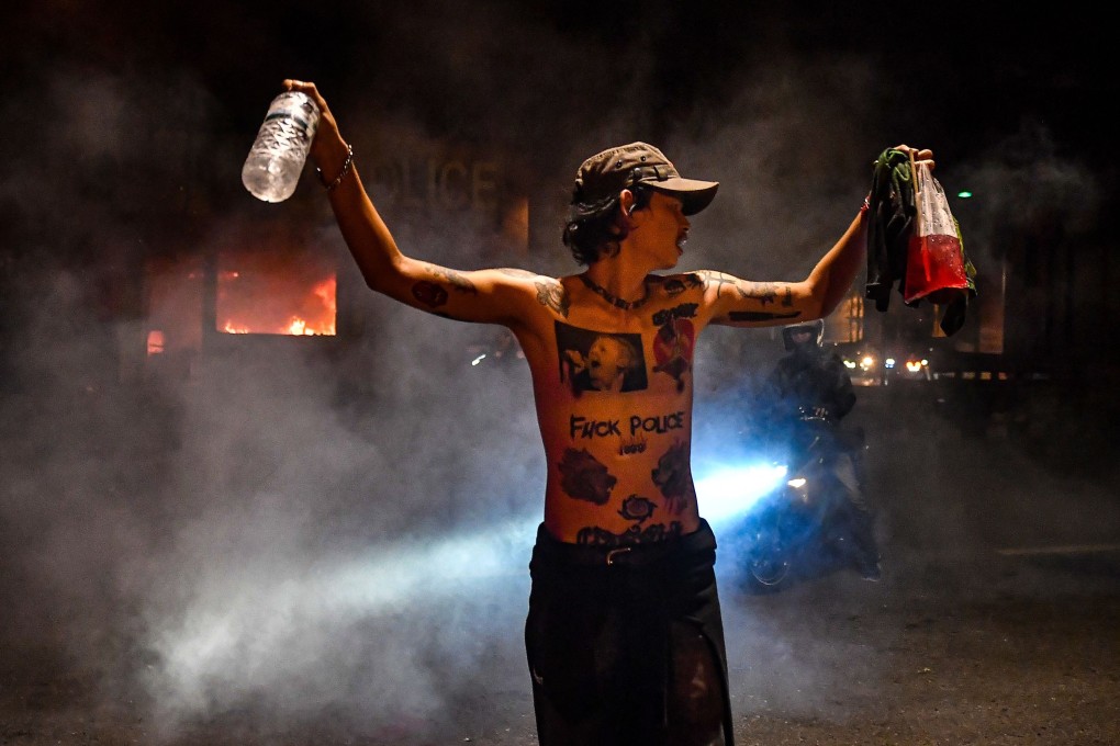 A protester gestures in front of a police post set on fire during a demonstration in Bangkok, Thailand on Sunday. Photo: AFP