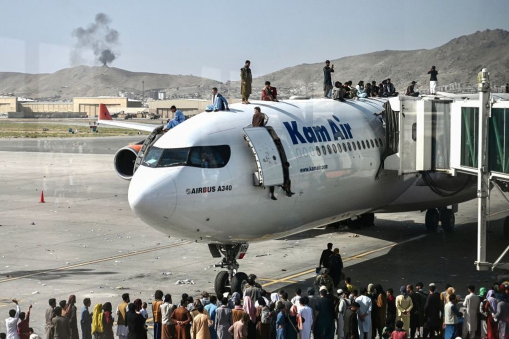 Afghans climb atop a plane as they wait at the Kabul airport on Monday. Photo: AFP via Getty Images/TNS