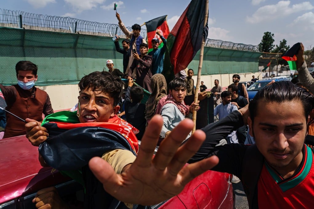 People carrying Afghanistan’s national flag march in the streets of Kabul despite the presence of Taliban fighters around them. Photo: TNS