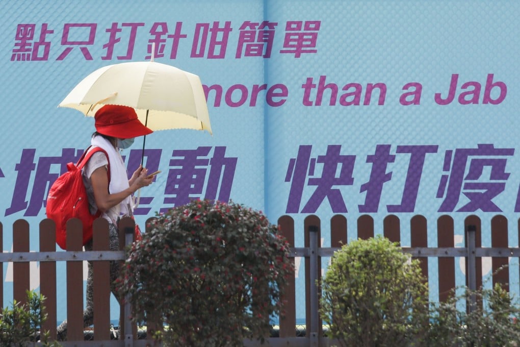A woman walks past a sign urging Hong Kong residents to get vaccinated. Photo: Xiaomei Chen