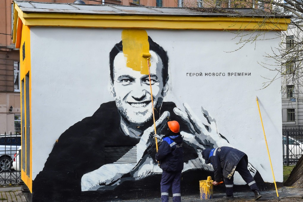A worker paints over graffiti of jailed Kremlin critic Alexei Navalny in Saint Petersburg in April. The inscription reads: “The hero of the new times.” Photo: AFP