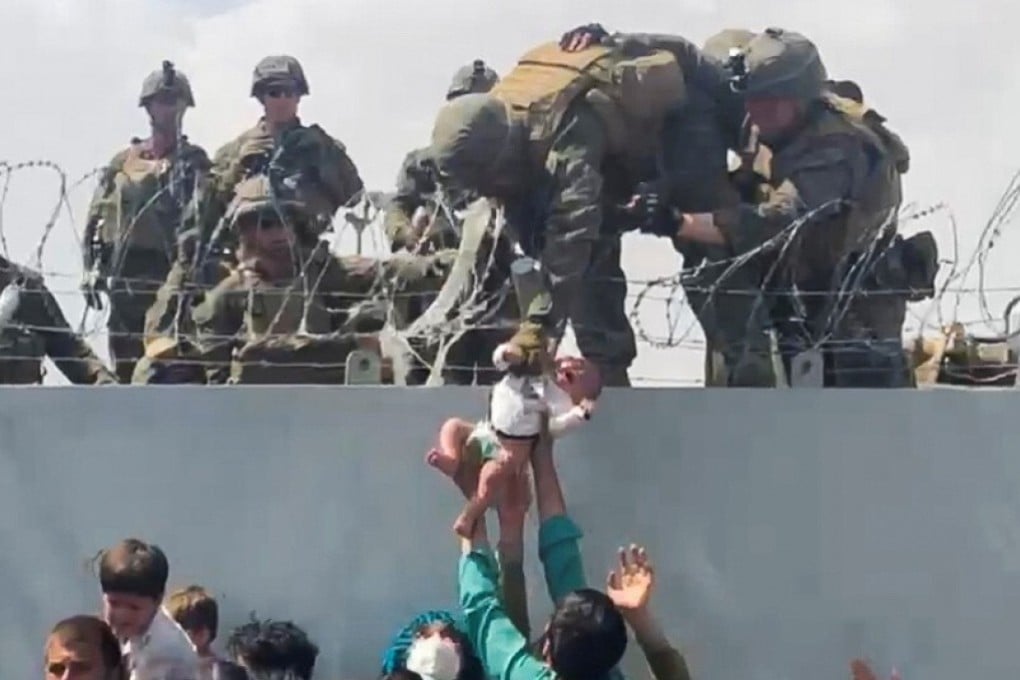 A baby is handed over to the American soldiers over the perimeter wall of Kabul airport on Thursday. Photo: Omar Haidari via Reuters