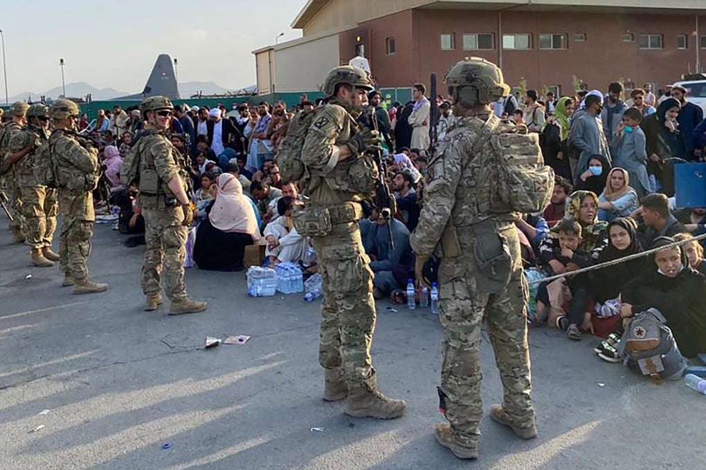 US soldiers stand guard as Afghan people wait to board a US military aircraft in Kabul. Photo: AFP