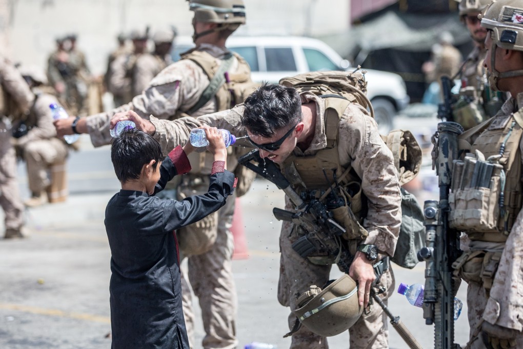 A US Marine and a child spray water at each other during the evacuation from Hamid Karzai International Airport in Kabul. Photo: Reuters