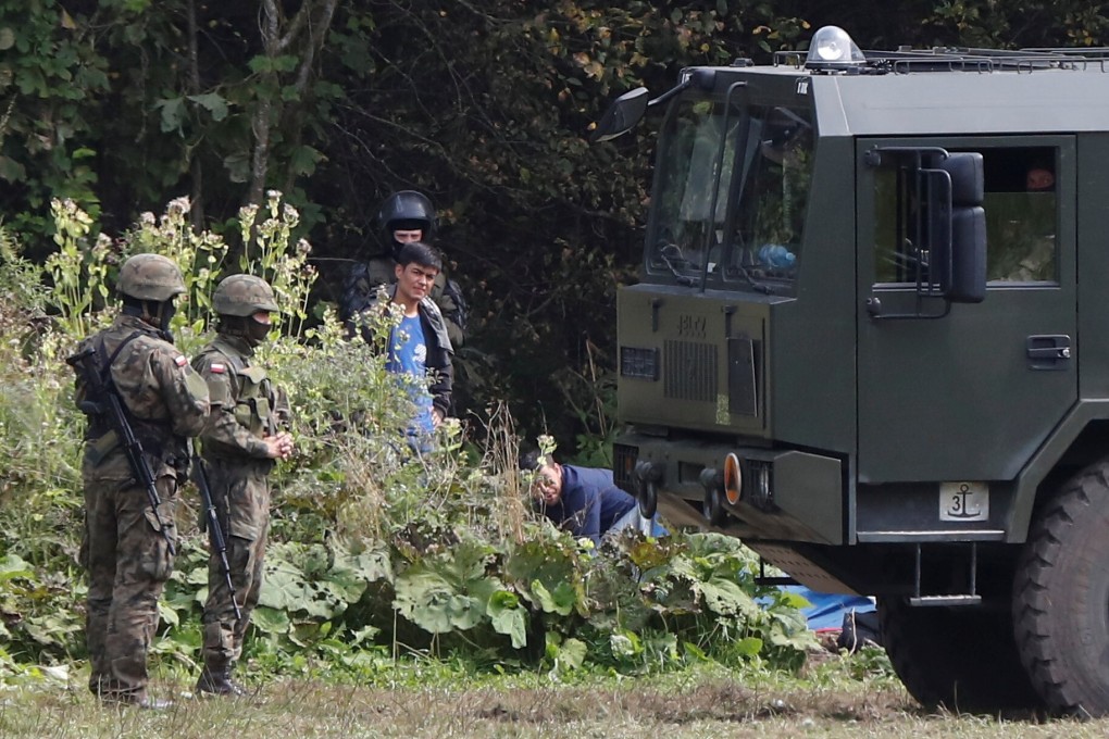 Polish border patrol officers next to a group of migrants stranded on the border between Belarus and Poland near the village of Usnarz Gorny, Poland on Monday. Photo: Reuters