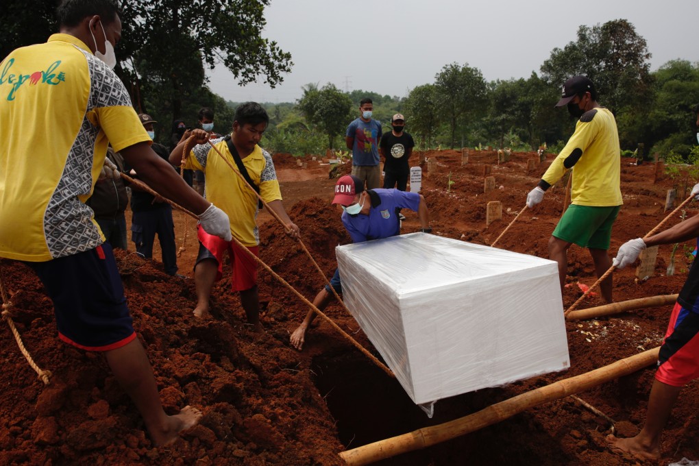 Cemetery workers bury the coffin of a Covid-19 victim during a funeral in Depok, Indonesia. The country has extended the current restrictions on community activities until the end of the month. Photo: EPA-EFE