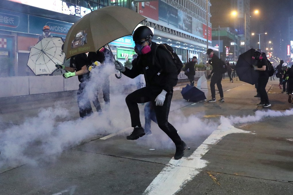 A protester tries to clear away a tear gas cannister during clashes with police in Mong Kok on October 27, 2019. Photo: Sam Tsang