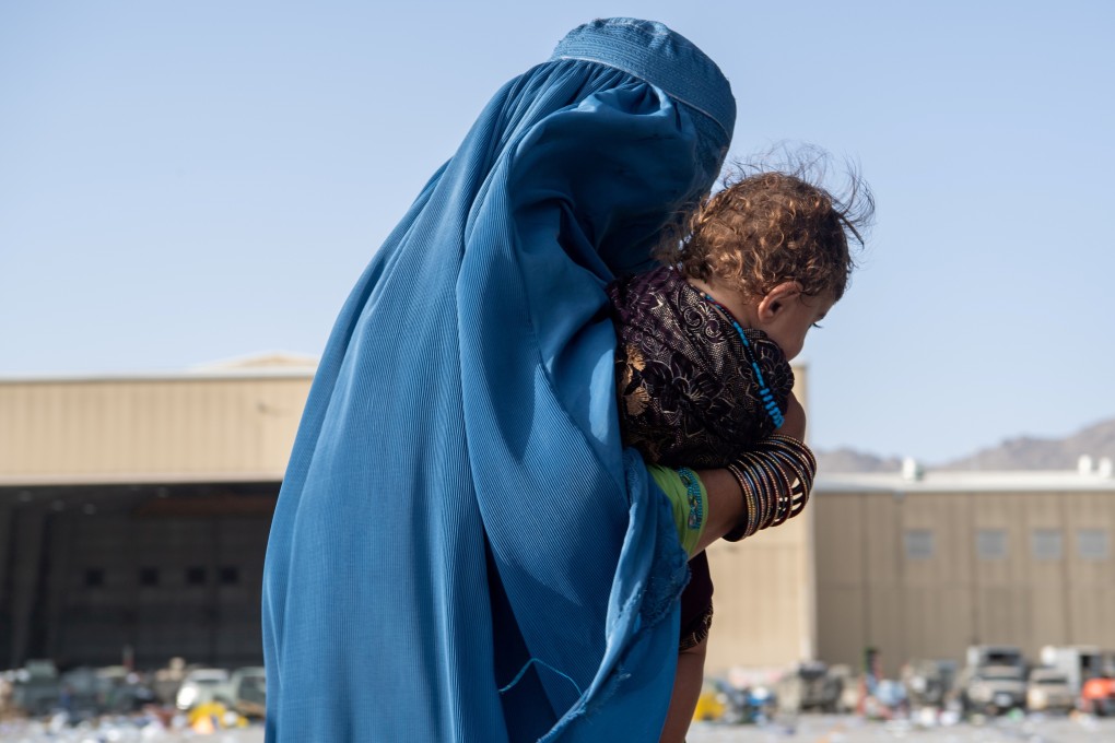 A woman carries a child as passengers board a US Air Force plane supporting the Afghanistan evacuation at Kabul. Photo: US Air Force/Handout via Reuters