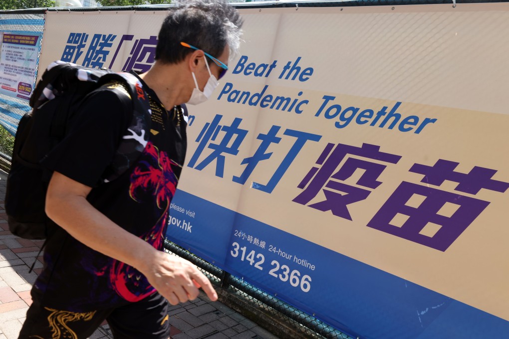 A man passes a government banner in Causeway Bay encouraging residents to get vaccinated. Photo: Nora Tam