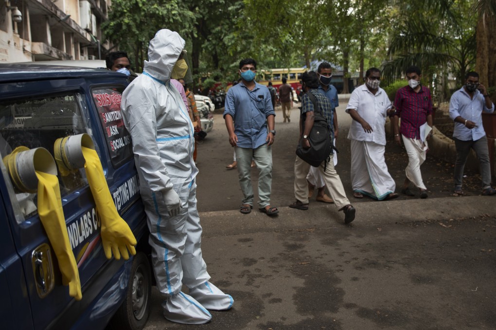 A man in a protective suit stands next to a mobile Covid-19 testing kiosk outside the Ernakulam district administration headquarters in Kochi, Kerala state, India. Photo: AP