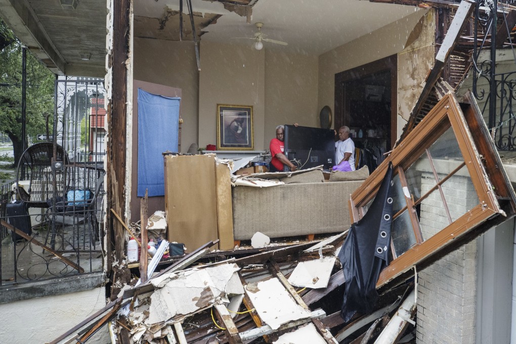 A man helps his friend remove items from his New Orleans home after the hurricane. Photo: AP