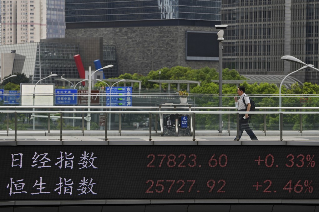 A man walks on an overhead bridge with an electronic board showing stock market indexes. Photo: AP