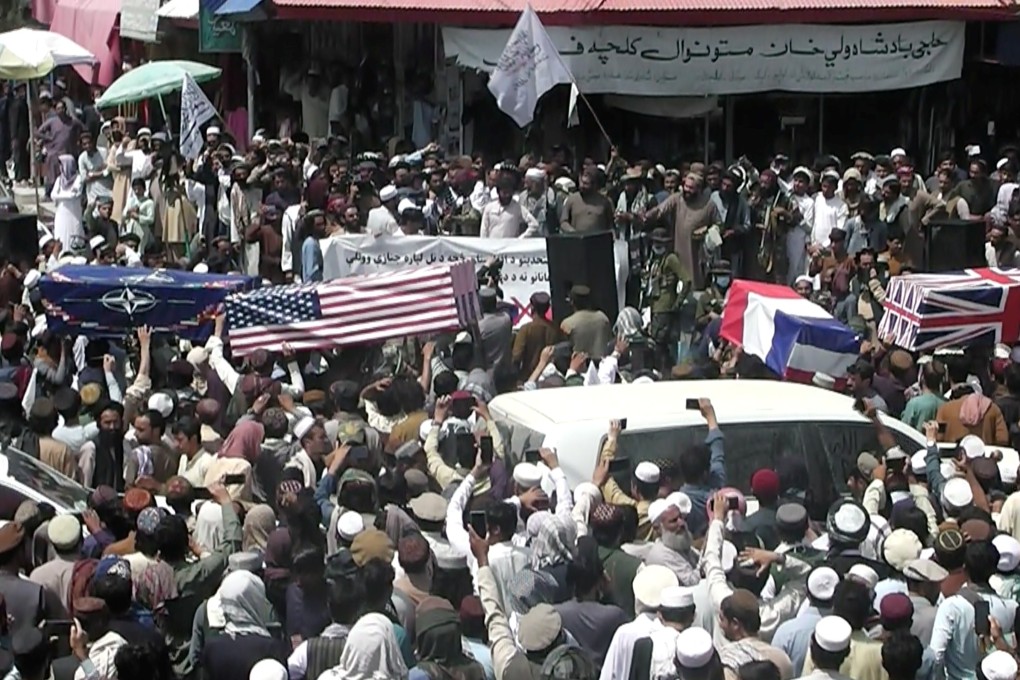 A crowd carries makeshift coffins draped in the flags of Nato, the United States and Britain during a pretend funeral on a street in Khost, Afghanistan on Tuesday. Photo: ZHMAN TV via Reuters