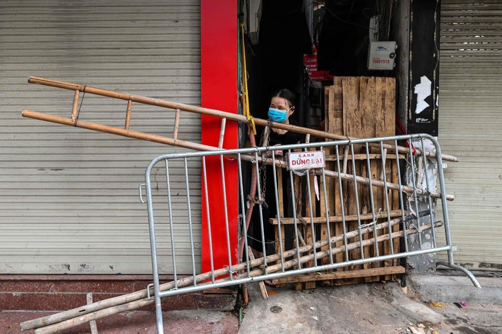 A woman looks out from behind an improvised barricade in Hanoi. Photo: AFP