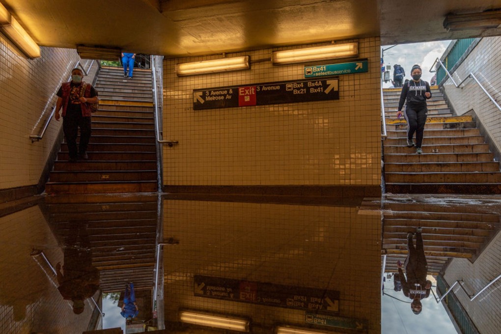 Commuters walk into a flooded Third Avenue/149th Street subway station in New York City. Photo: AFP