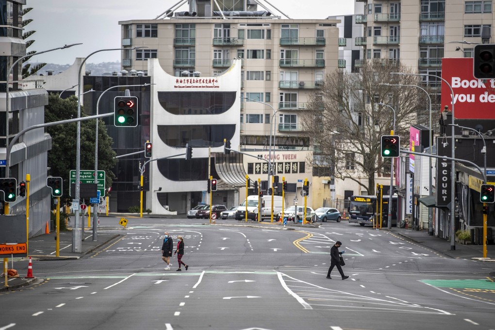 People cross nearly empty streets in the central business district of Auckland, New Zealand. Photo: NZ Herald via AP