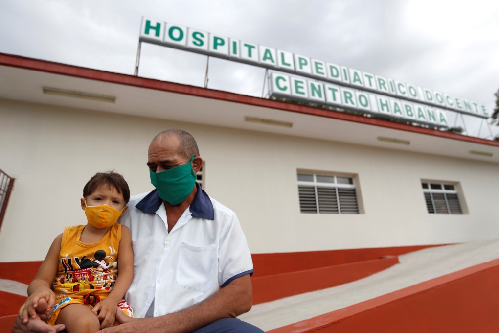 A man holds his son outside a paediatric hospital in Havana, Cuba where young children can now receive the coronavirus vaccine. Photo: EPA-EFE