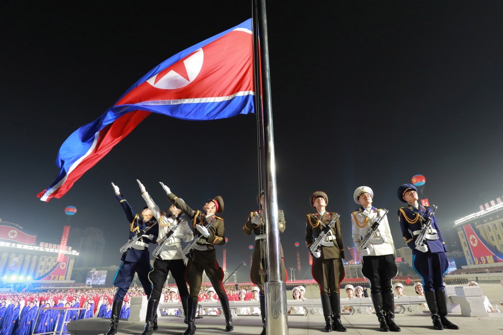 North Korean officials salute the country’s flag during the military parade at Kim Il-sung Square in Pyongyang. Photo: EPA