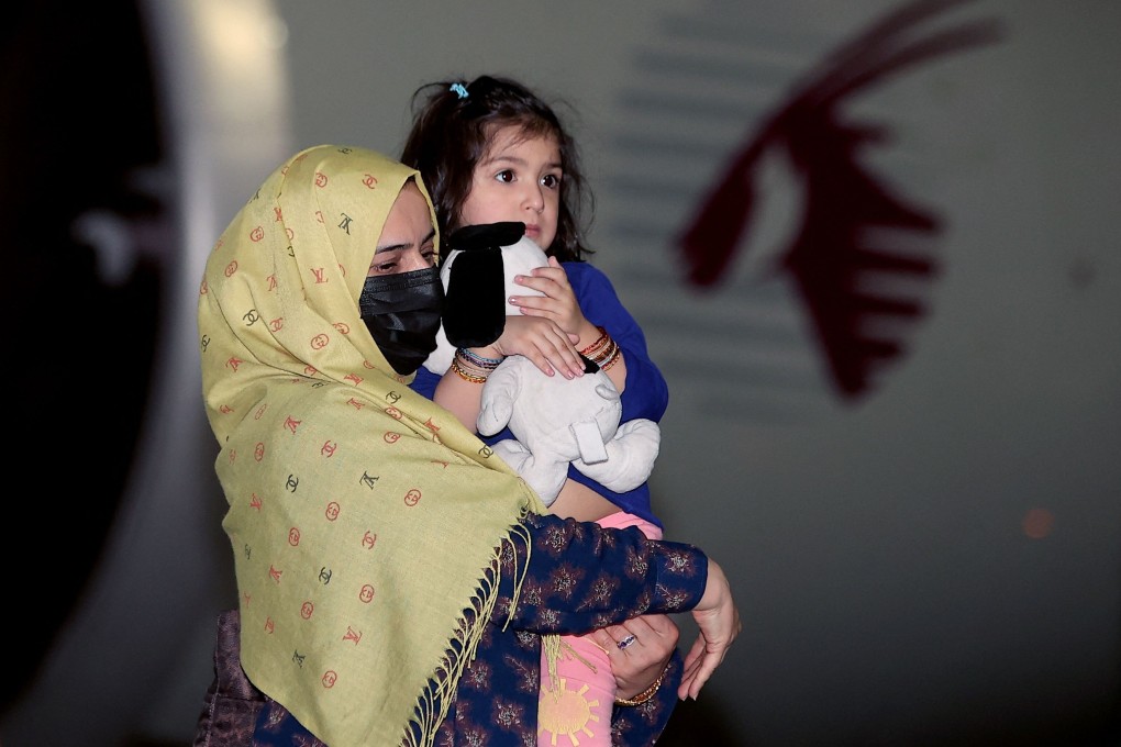 A woman carries a child as they arrive with other evacuees from Afghanistan at Hamad International Airport in Qatar's capital Doha on Thursday. Photo: AFP