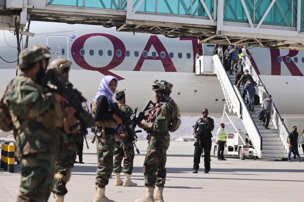 Taliban fighters stand guard as passengers disembark from a Qatar Airways flight in Kabul. Photo: AFP