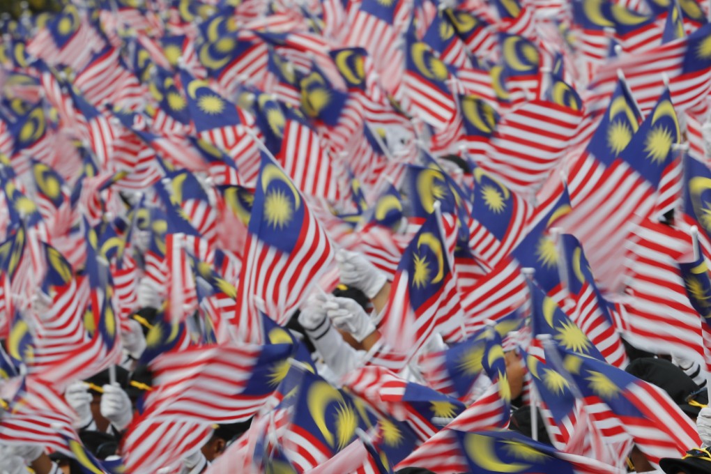 Students wave national flags during Independence Day celebrations in Malaysia. Photo: AP