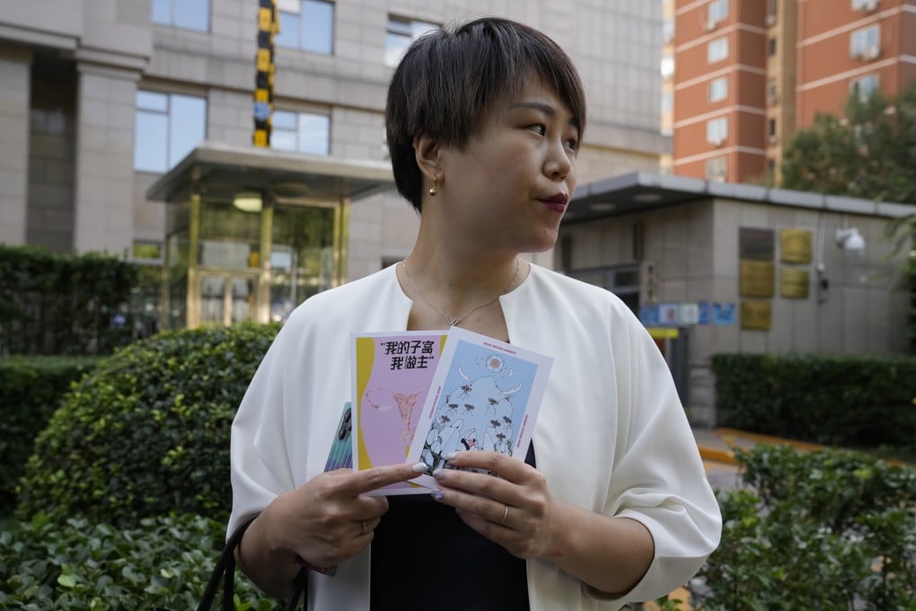 Teresa Xu holds up cards one of which reads “My Womb, My Choice” before attending a court session in Beijing on Friday. Photo: AP