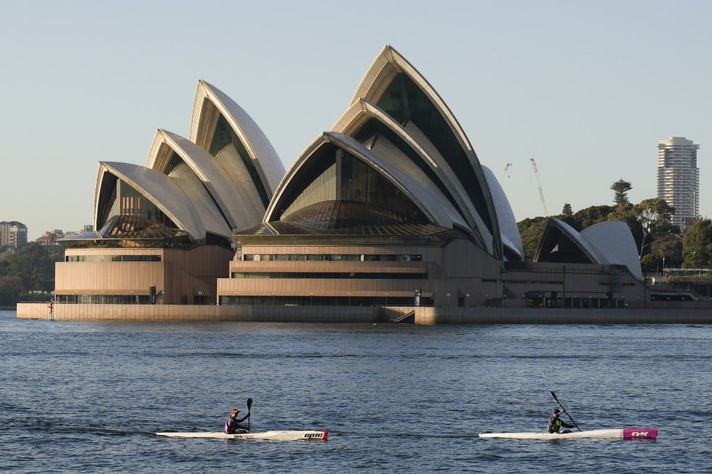 Kayakers paddle past the Opera House on Sydney Harbour on Friday. Photo: AP